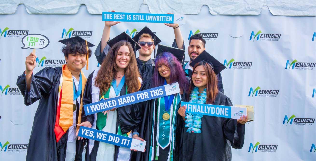happy graduates pose with signs